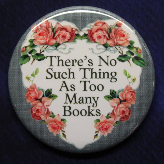 Round button badge with floral design and text 'There's No Such Thing As Too Many Books' on a dark background